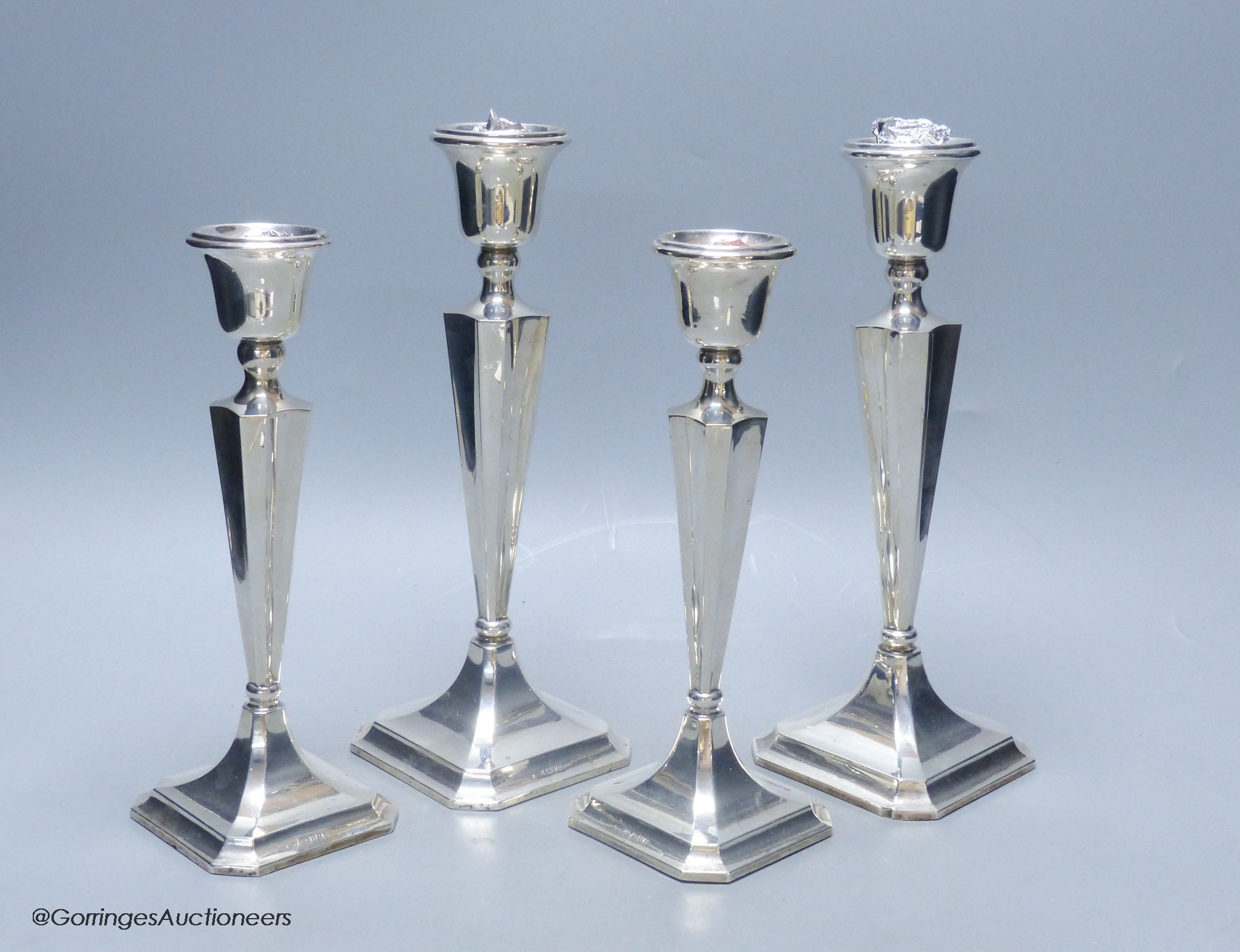 Two graduating pairs of George V silver candlesticks, James Deakin & Sons, Chester, 1925, weighted, tallest 26.1cm.